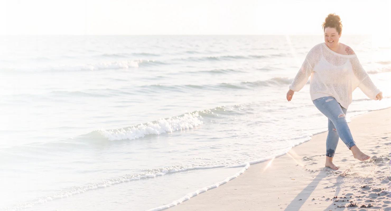 Monika walking along the sunlit shoreline